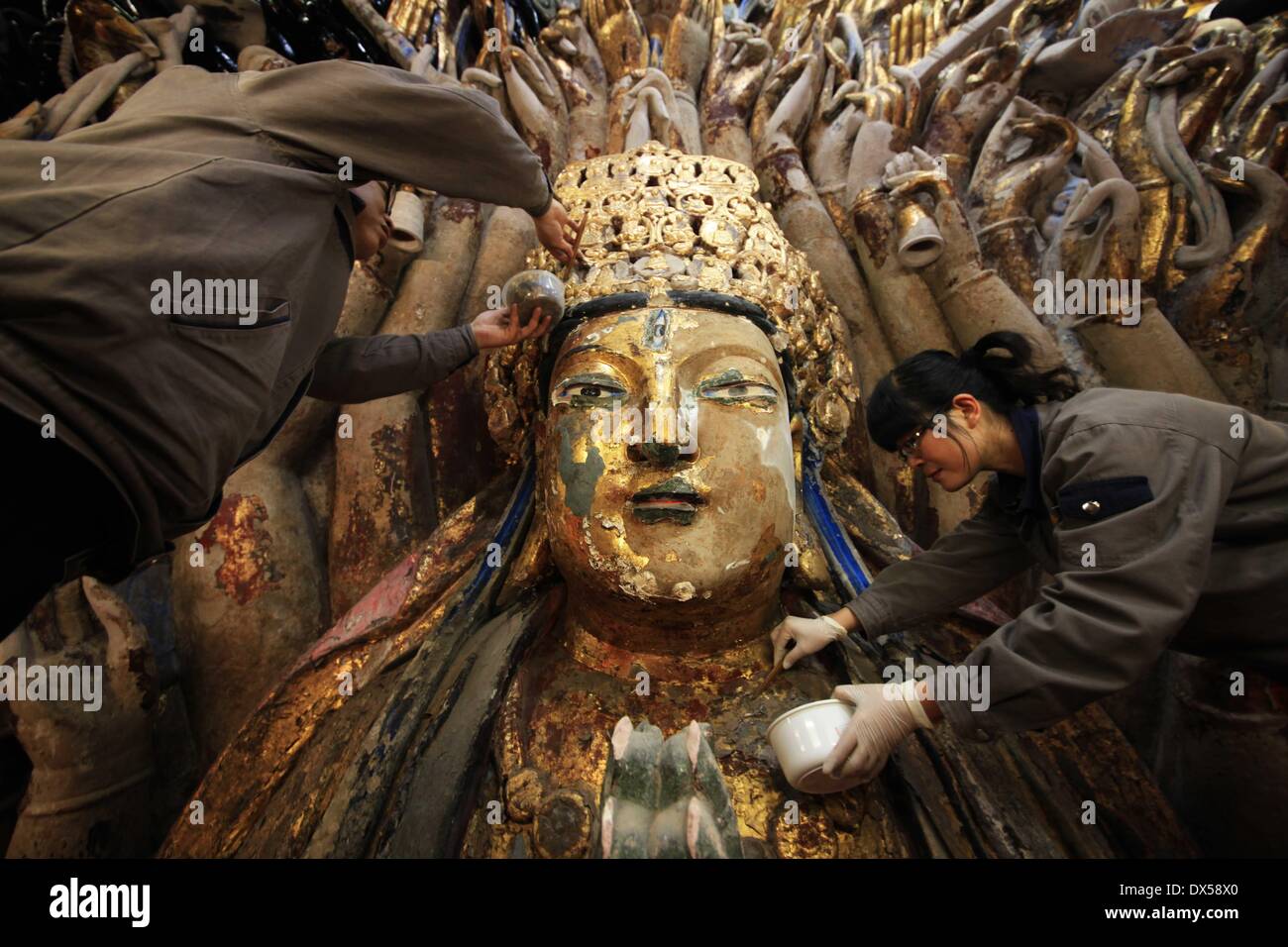 (140318)--CHONGQING, 18. März 2014 (Xinhua)--Personal Mitglieder klar gold Folie von der Skulptur der Qianshou Guanyin (Bodhisattva mit tausend Händen) auf Mount Baoding im Bezirk Dazu in der Gemeinde von Chongqing, Südwest-China, 18. März 2014 peeling. Die Skulptur geschnitzt in der Höhle mit 7,7 Meter hoch und 12,5 Meter breit, könnte südlichen Song-Dynastie (1127 bis 1279) stammen. Im Laufe der Jahrhunderte die Skulptur Farbe ist verblasst, Teile der Goldfolie Verkleidung haben abgeschält und Risse aufgetreten. Und somit ein Restaurierungsprojekt für die buddhistische Statue wurde gestartet Stockfoto