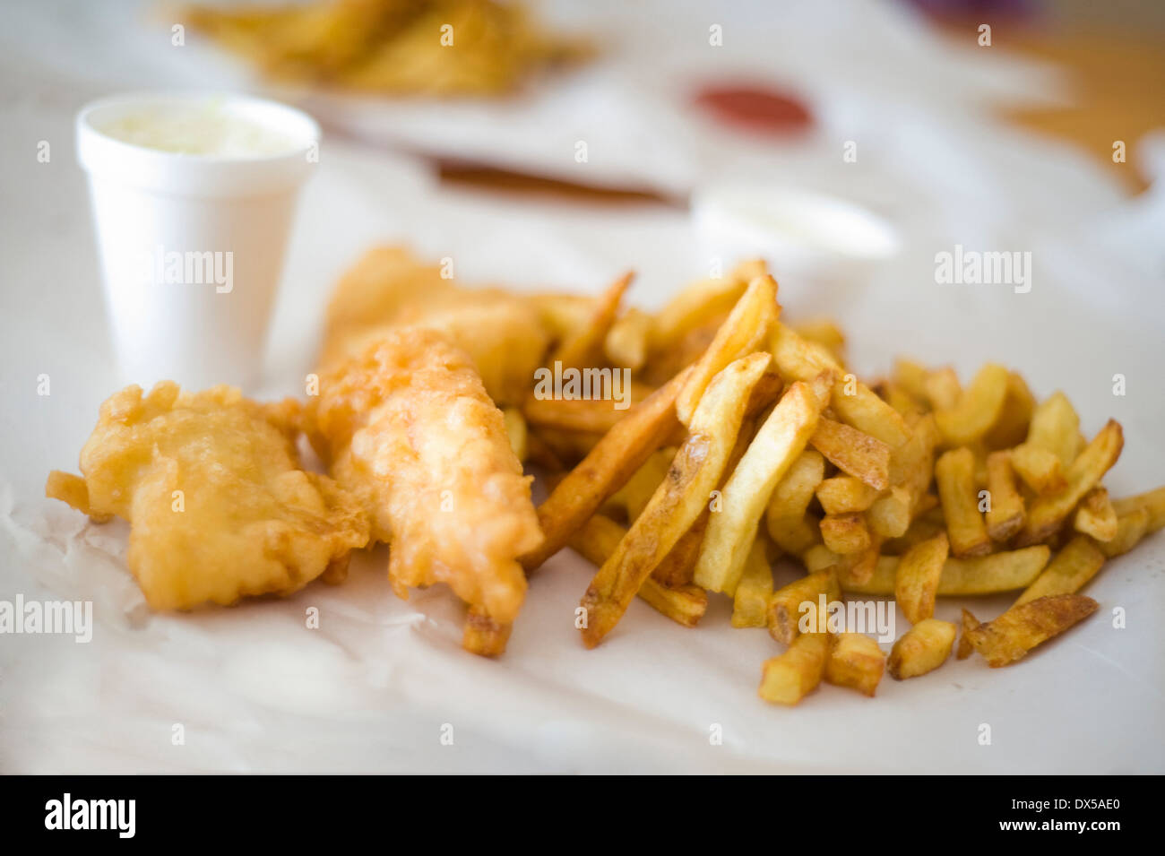 Take-out Fish &amp; Chips auf braunem Papier mit einer Seitenlänge von Krautsalat in einer Styropor-Tasse Stockfoto