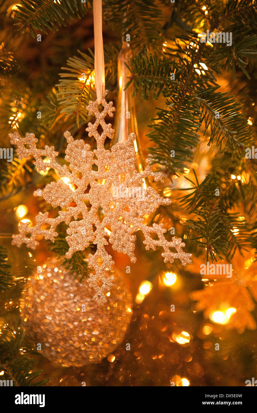 Glitzernde Schneeflocke und Ball Ornamente in beleuchtete Weihnachtsbaum hängen Stockfoto