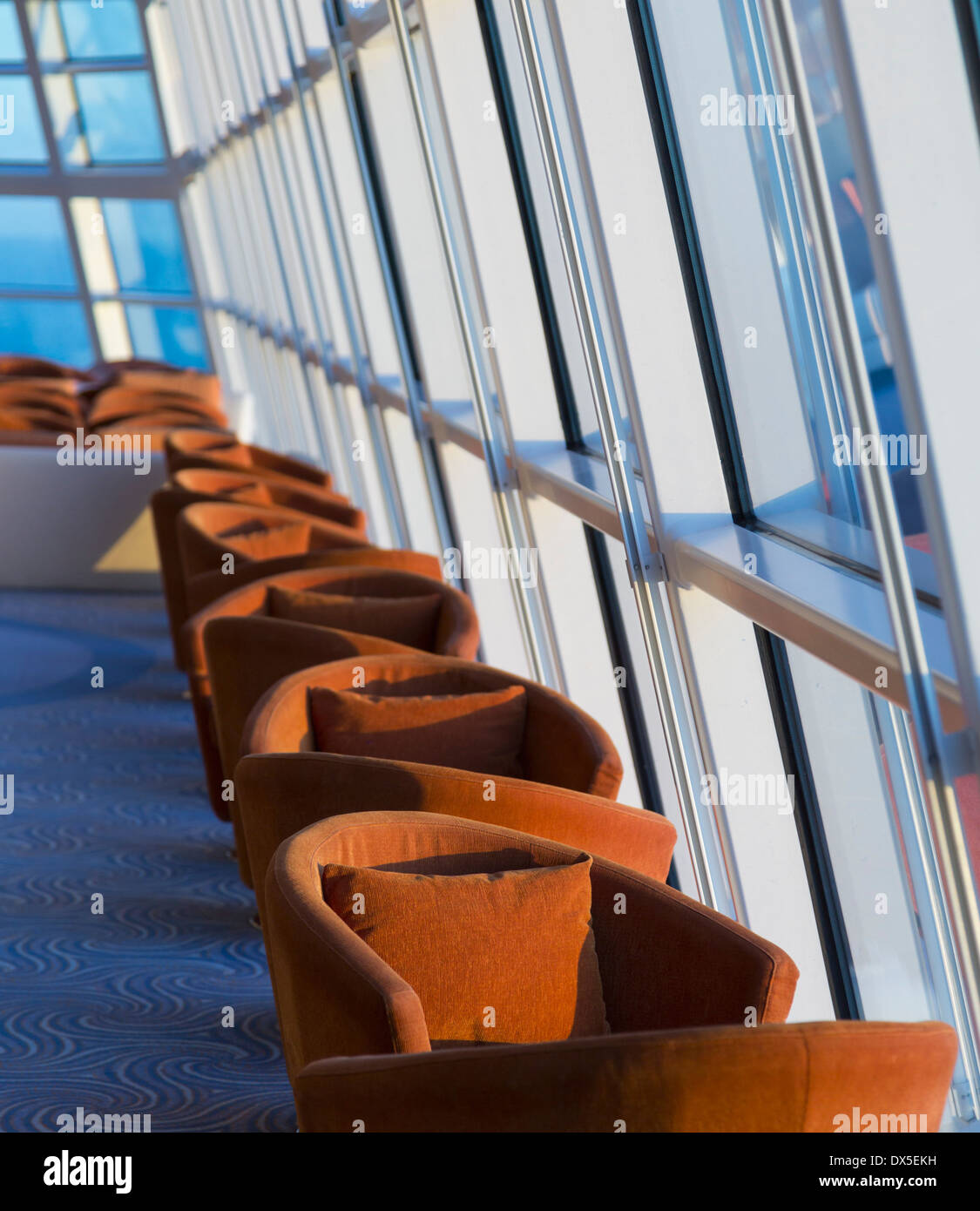 Sitzreihe durch hohe Glasfenster mit Blick auf das Meer auf einem Kreuzfahrtschiff Stockfoto