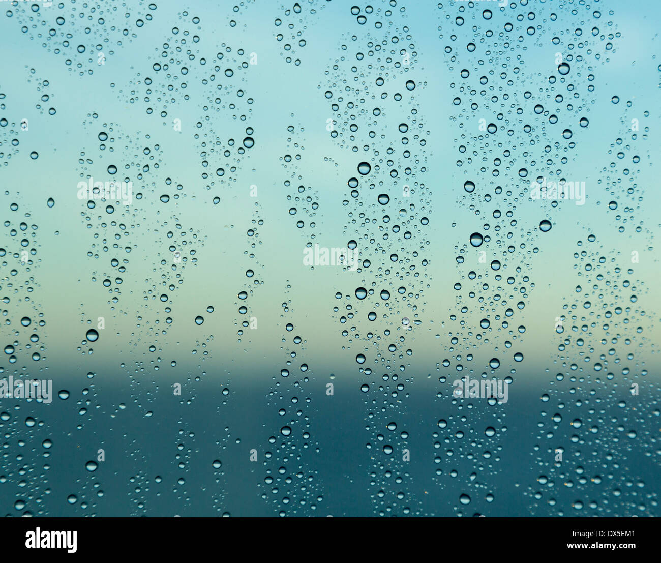 Regentropfen auf ein Fenster mit Blick auf das Meer in der Morgendämmerung Stockfoto