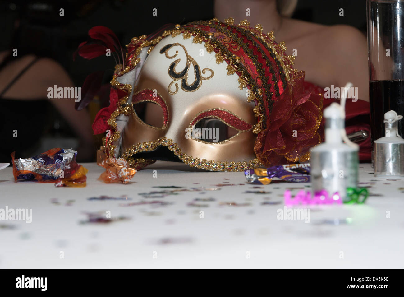 Eine ausrangierte Maske auf einer Party auf einem Tisch mit Konfetti und poppers Stockfoto