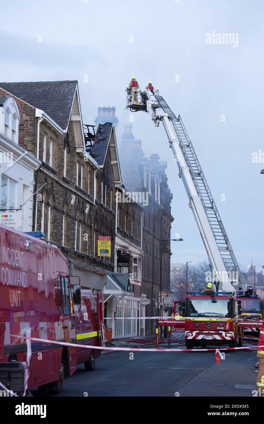 Mutige Feuerwehrmann Mannschaft hohe Leiter (vom Motor) Bekämpfung des Feuer mit Wasser am Zentrum Gebäude - Harrogate, North Yorkshire, England, UK. Stockfoto