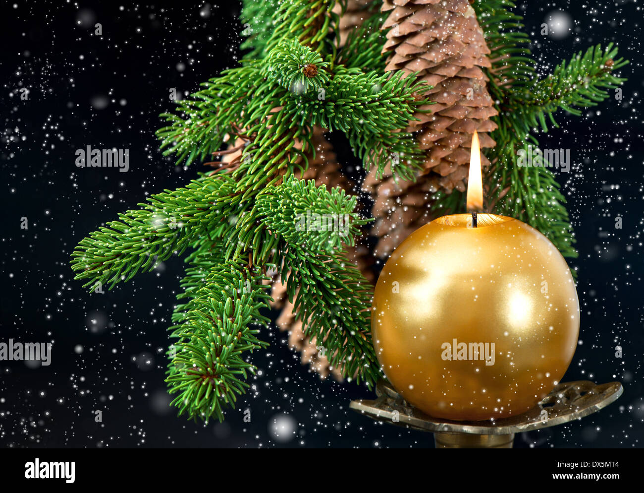 Weihnachtsbaum Zweig mit goldenen brennende Kerze über schwarzen Hintergrund mit Schneefall-Effekt Stockfoto