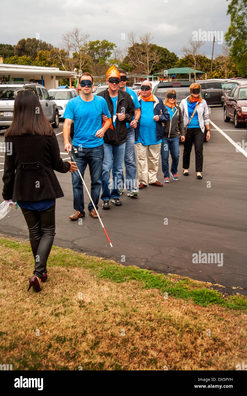 Besucher zu einer Schule für Blinde in Tustin, Kalifornien, werden die Augen verbunden um die es ihnen ermöglichen, Blindheit zu erleben, wie sie lernen, einem Blindenstock zu benutzen, um zu Fuß auf einem Parkplatz. Stockfoto
