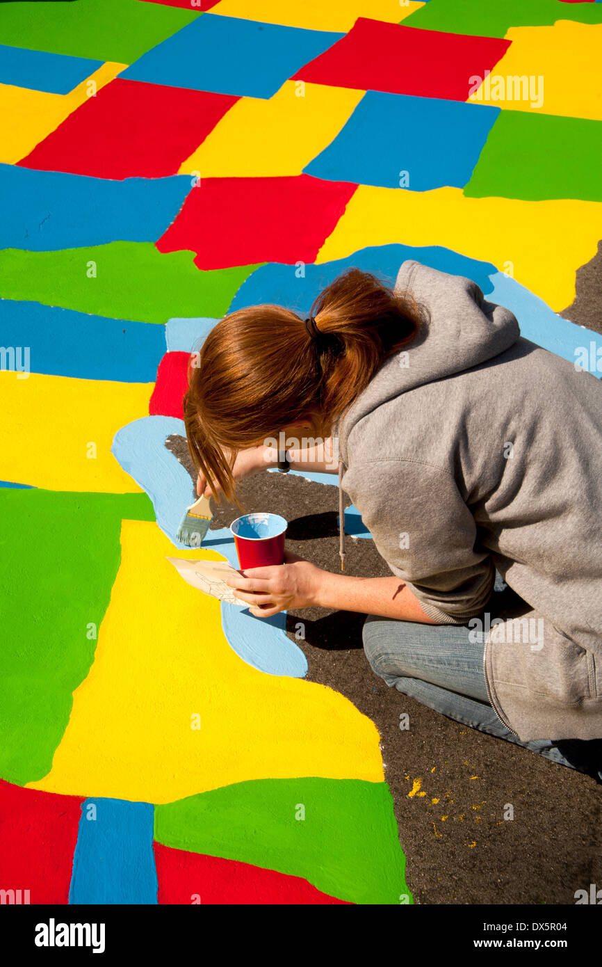 Ein junger Erwachsener freiwilliger Künstler malt den großen Seen auf einer Karte von den Vereinigten Staaten in einer Grundschule Spielplatz in Garden Grove, Kalifornien. Stockfoto
