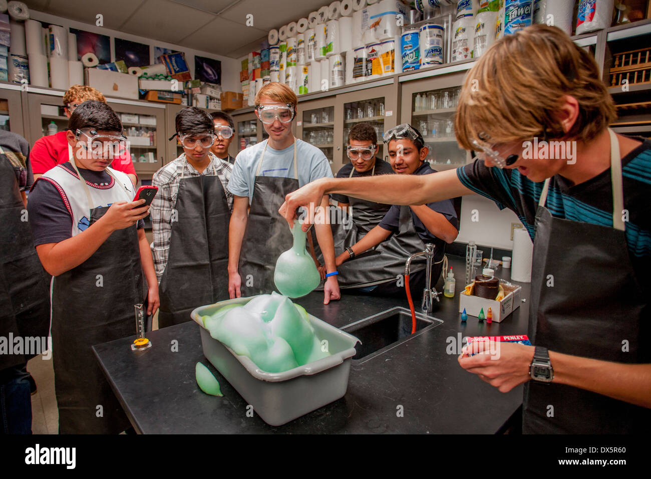 Gemischtrassig San Clemente, CA, Gymnasium Chemie Schüler zusehen, wie Wasserstoffperoxid, Seife und Natriumiodid sind gemischt, um eine expandierende Schaum Sauerstoff gefangen in daraus resultierenden Seifenblasen erzeugen. Hinweis: Handy-Kameras, Schutzbrille und Schürzen. Stockfoto
