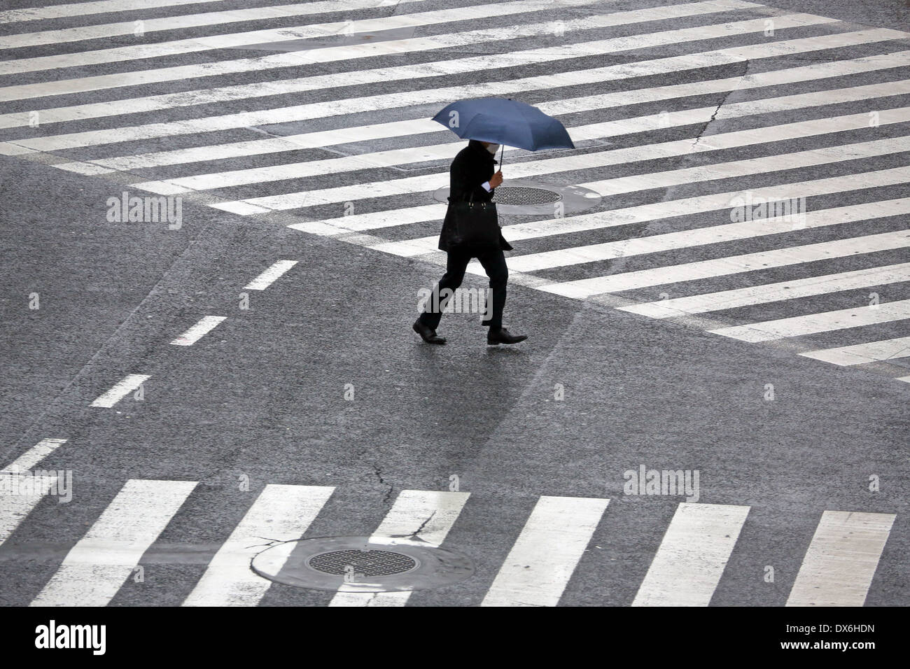 Menschen, die Sonnenschirme in den Regen zu Fuß über den Fussgängerstreifen in Shibuya, Tokyo, Japan Stockfoto