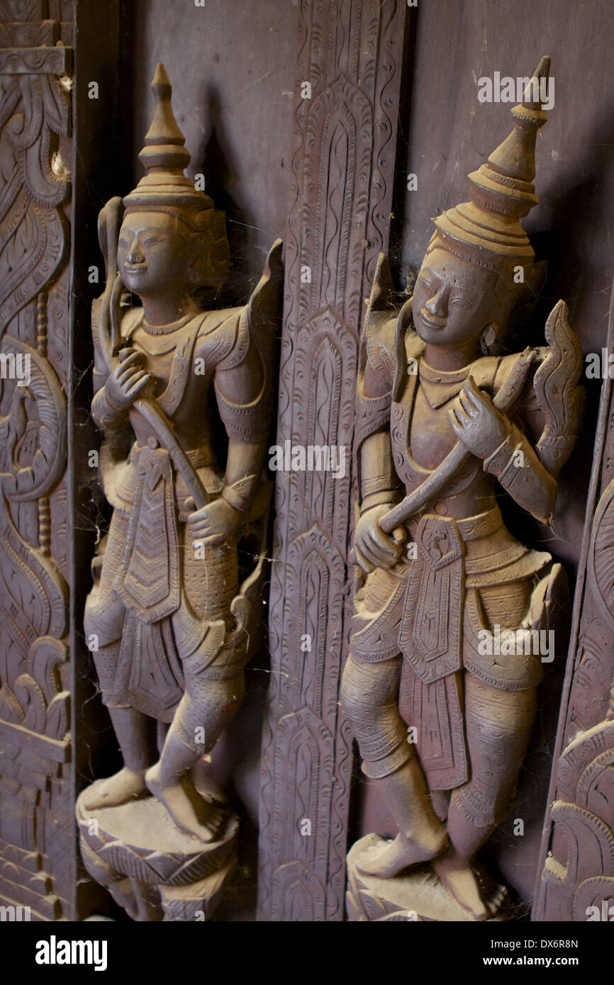 Spinnennetz bedeckt geschnitzte Holzfiguren auf Platten und Türen innerhalb der Shwe In Bin Kyaung Kloster, ein aus Teakholz in Mandalay Stockfoto