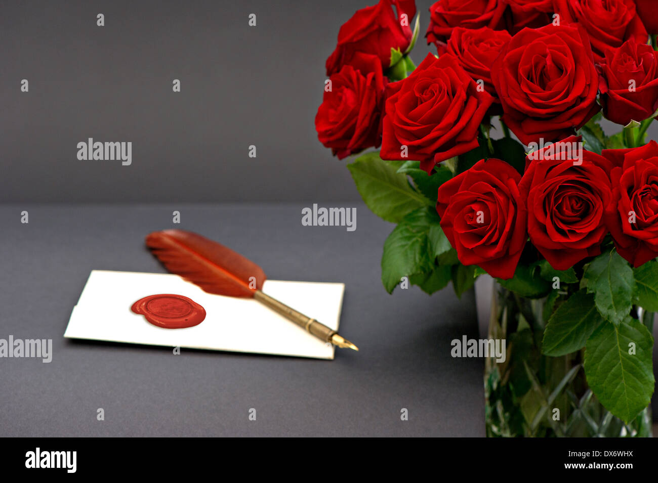 Bouquet von roten Rosen und Liebesbrief auf schwarzem Hintergrund. festliche Blumen-arrangement Stockfoto