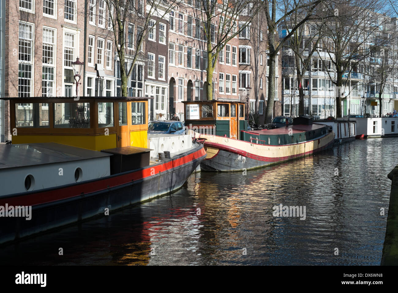 Kanal Lastkähne am Kanal in Amsterdam Niederlande mit historischen Lagerhallen im Hintergrund Stockfoto