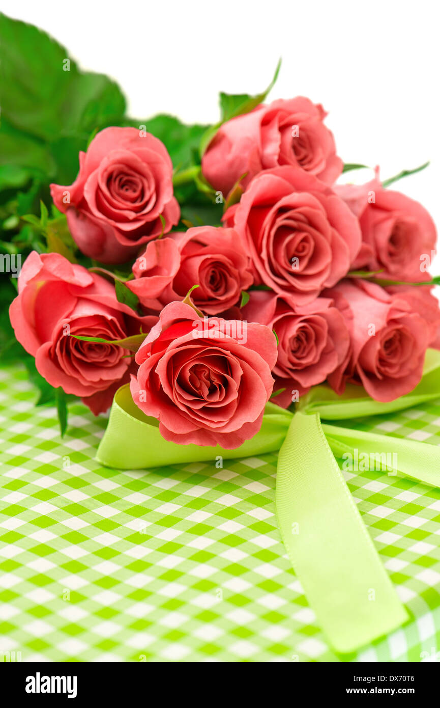 frische rosa Rosen mit Geschenk auf weißem Hintergrund. festliche Blumen und Vase Stockfoto