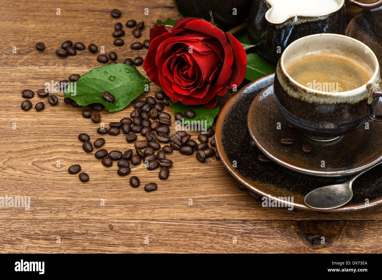 Tasse schwarzen Kaffee und rote rose Blume auf hölzernen Hintergrund. Festliches arrangement Stockfoto