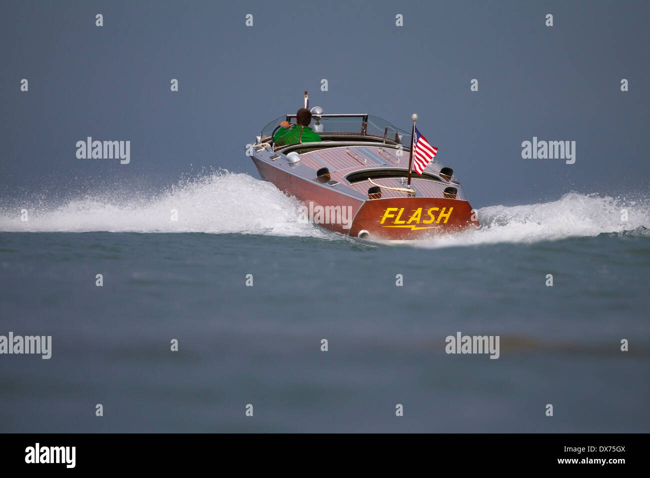 Ein Mann, der ein antikes, hölzernes Hacker-Craft-Boot mit Geschwindigkeit fährt. Stockfoto