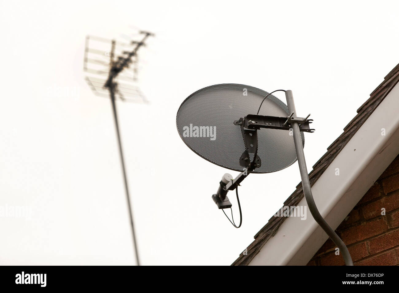 eine TV-Satellitenschüssel und eine TV-Antenne auf einem Haus Stockfoto