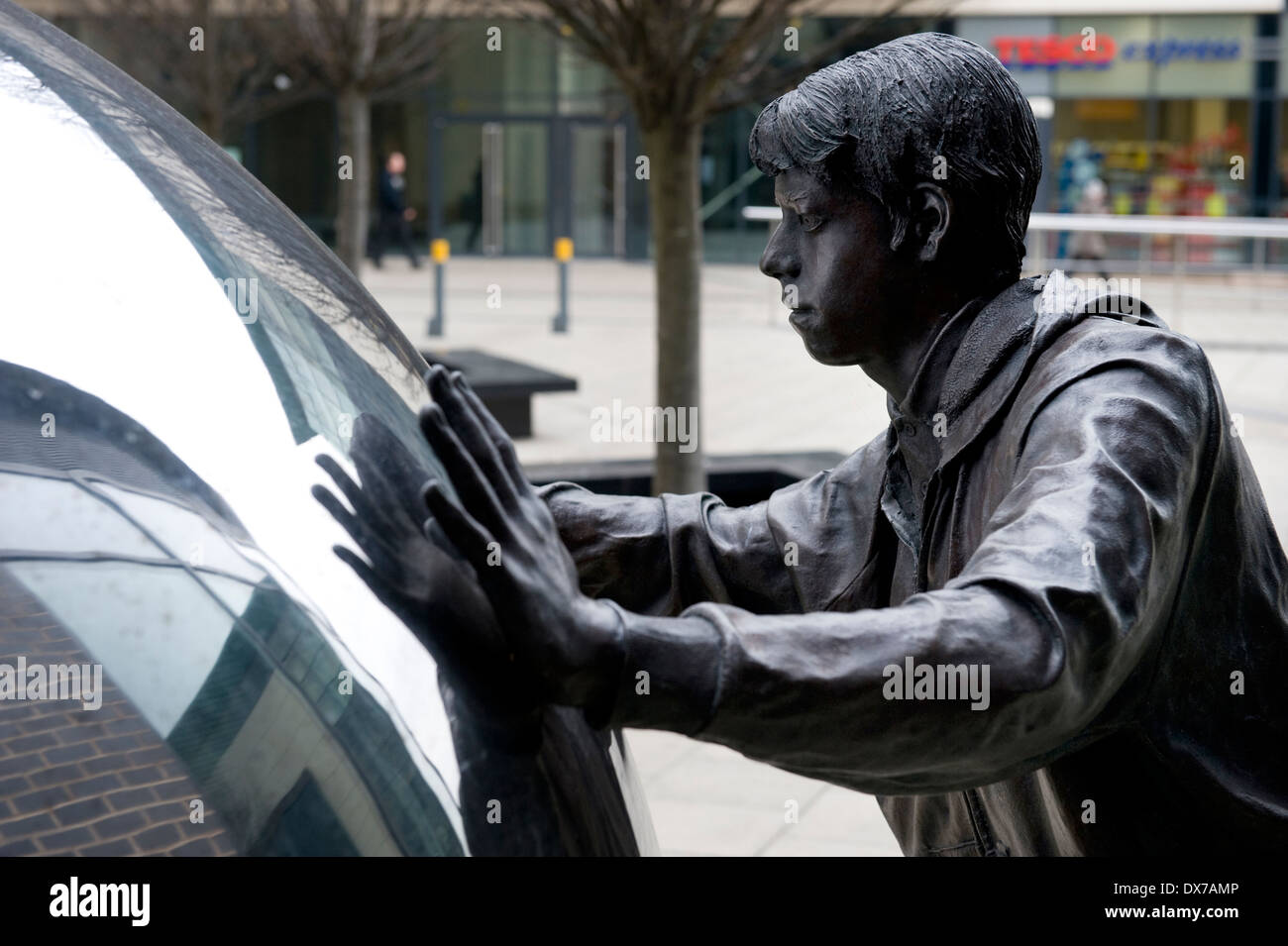 Skulptur im neuen Dock, ehemals Clarence Dock, Leeds, zeigt Leben Größe Bronze Figur schieben Edelstahlkugel. Stockfoto