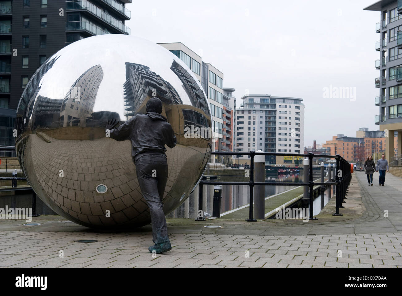 Skulptur im neuen Dock, ehemals Clarence Dock, Leeds, zeigt Leben Größe Bronze Figur schieben eine Kugel aus Edelstahl. Stockfoto