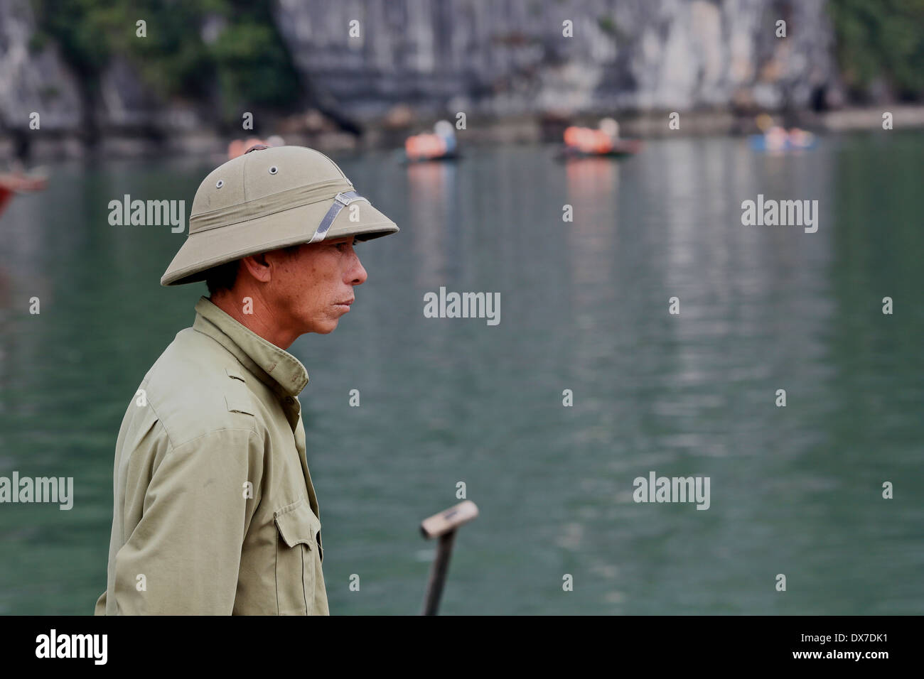 Vietnamesische Mann mit einem herkömmlichen nordvietnamesischen Helm auf das schwimmende Dorf aus Dau Go Insel, Ha Long Bucht, Bucht von Tonki Stockfoto