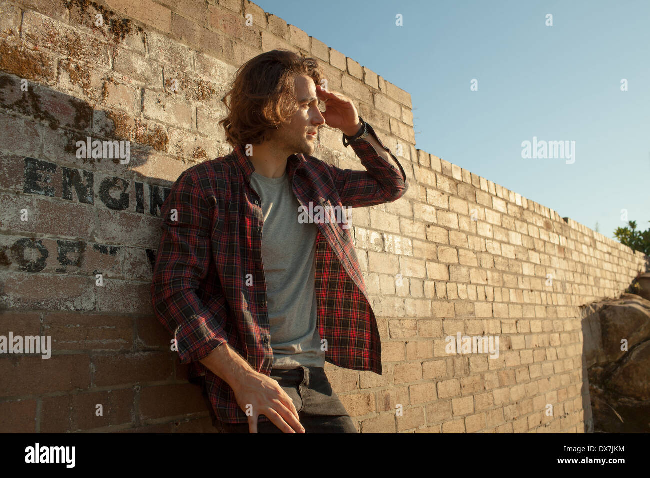 Ein junger Mann gegen eine rustikale Mauer fotografiert Stockfoto