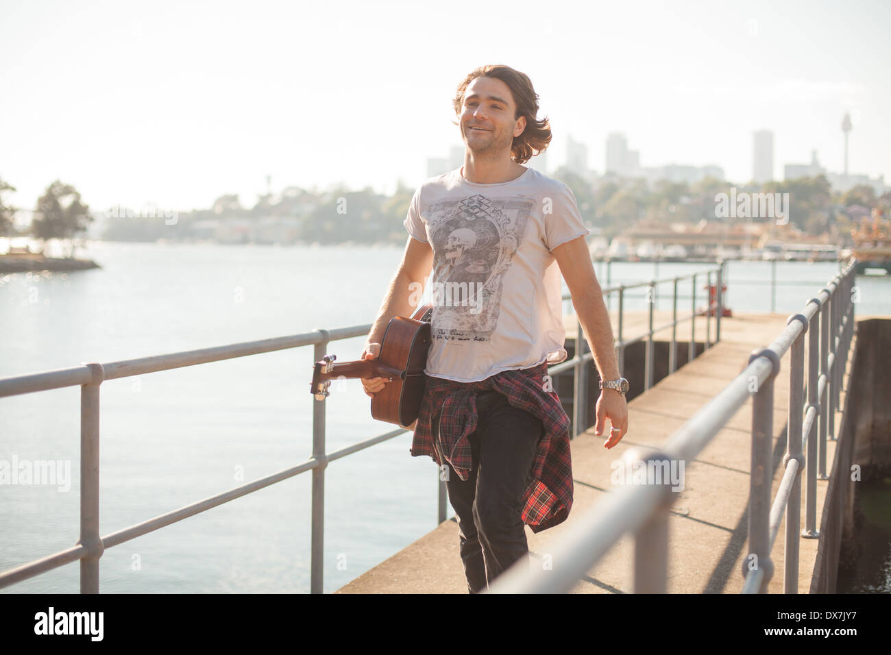 Ein gesunder junger Mann durch das Wasser im Hafen von Sydney mit seiner Gitarre Stockfoto