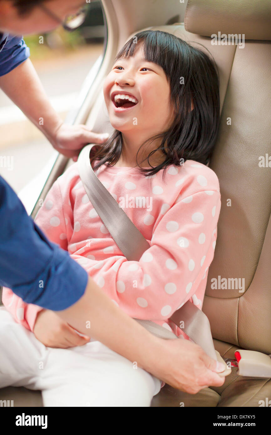 Vater kümmern Tochter einen Sicherheitsgurt im Auto befestigen Stockfoto