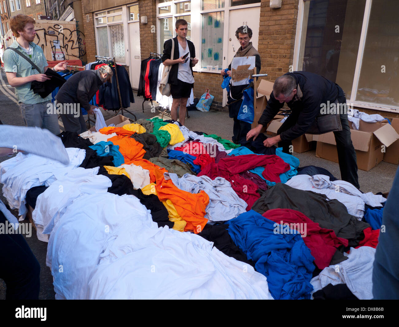 Straßenhändler, der farbenfrohe T-Shirts aus Baumwolle für £1 $ in einer Straße in der Nähe von Brick Lane East London E1England Großbritannien KATHY DEWITT verkauft Stockfoto