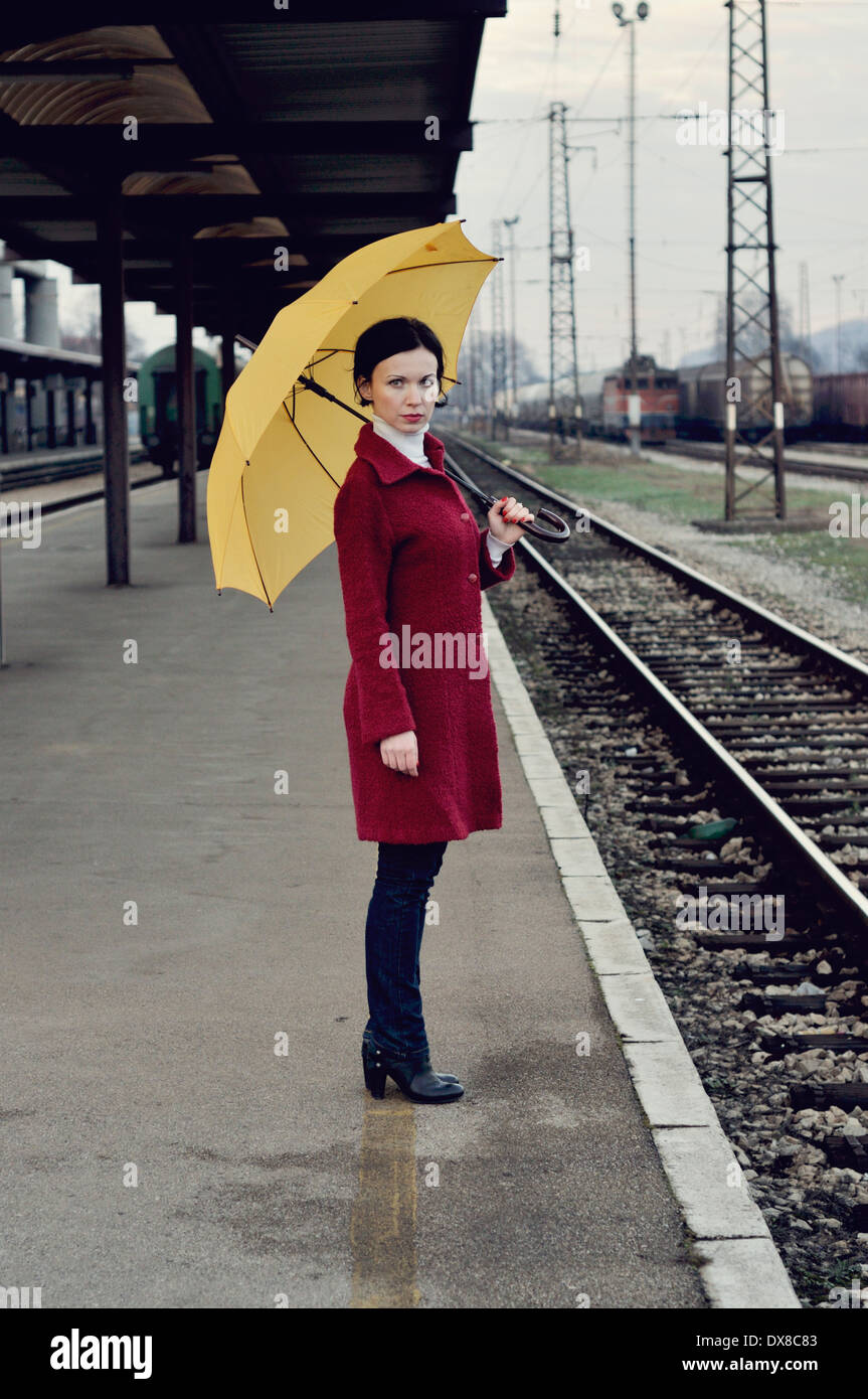 Mitte Erwachsene Frau auf Eisenbahn Bahnsteig hält Regenschirm Stockfoto