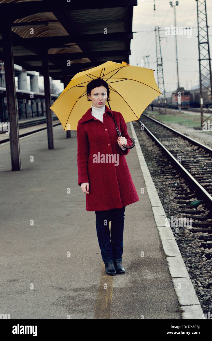 Mitte Erwachsene Frau auf Eisenbahn Bahnsteig hält Regenschirm Stockfoto