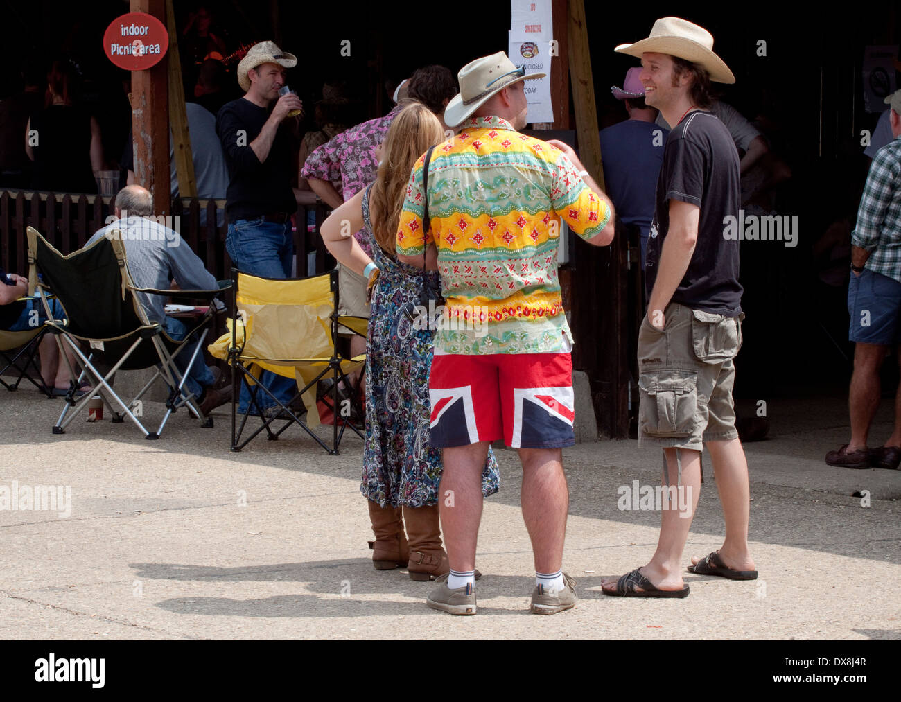 Zwei Männer im Gespräch und Cowboy-Hüte bei einem Outdoor-Musik-Festival.  Eine trägt beeindruckend große Stockfoto