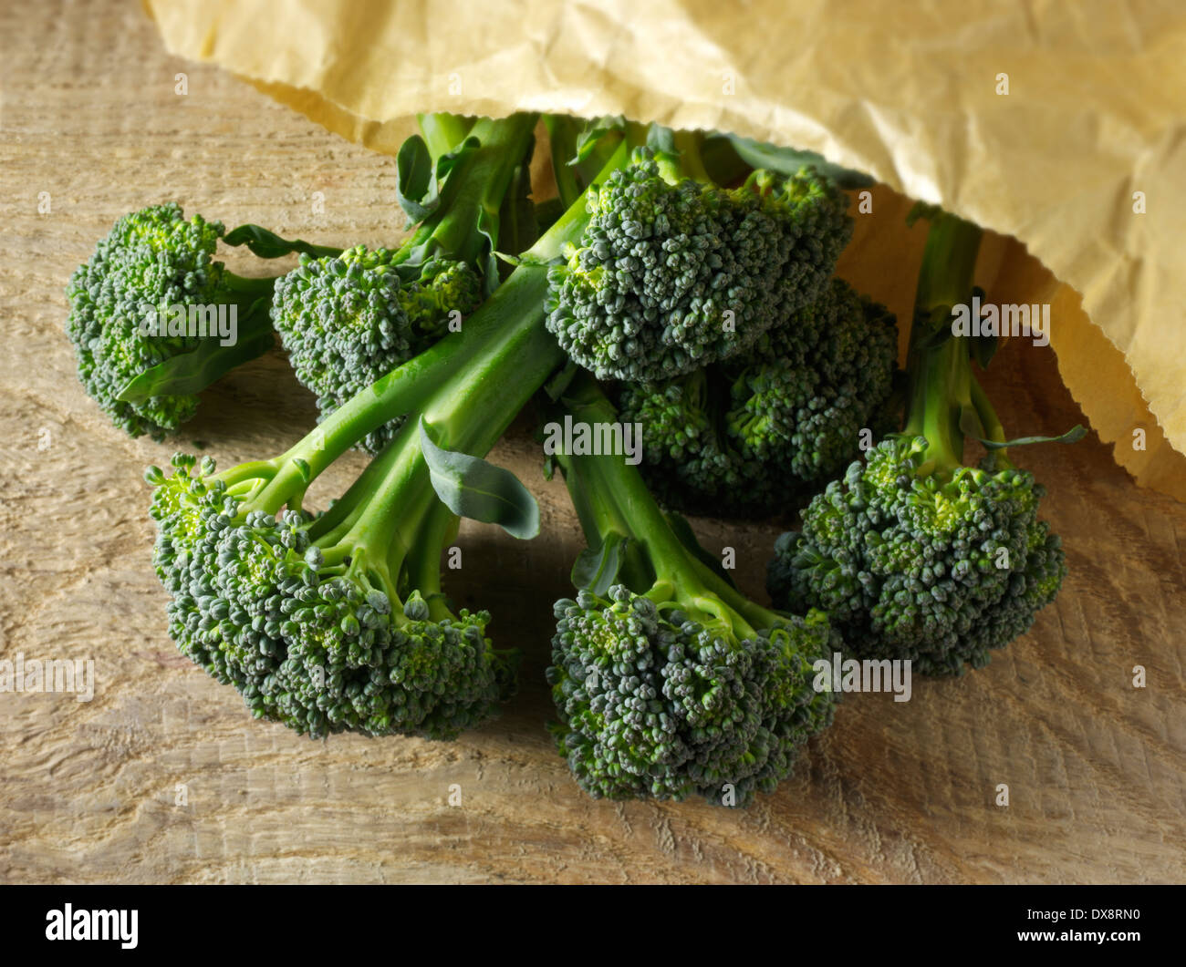Nahaufnahme der Brokkoli verschütten aus einer Papiertüte auf einer hölzernen Hintergrund, Top Shot Stockfoto