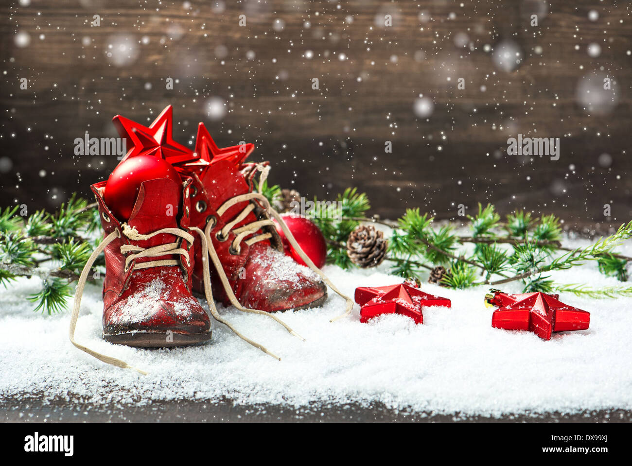 Vintage Weihnachten Dekoration rote Kugeln, Sterne und Antik baby-Schuhe auf hölzernen Hintergrund. Retro-Stil Bild mit Schneeflocken Stockfoto