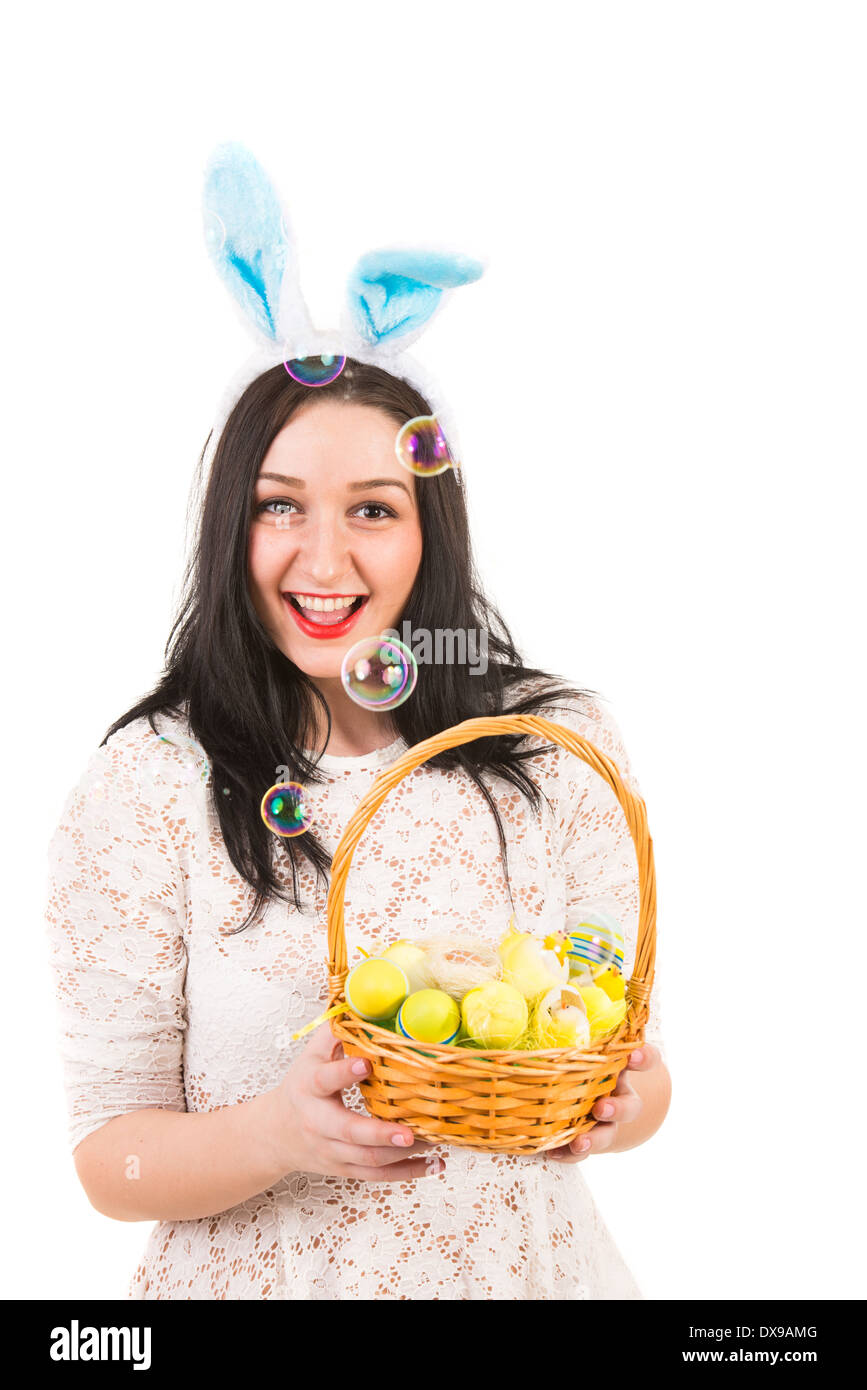Fröhliche Frau mit Hasenohren mit Osternest und Seifenblasen sind Ausblasen Stockfoto