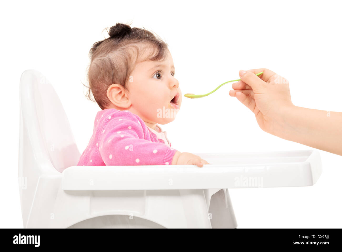Babymädchen gefüttert in einem Fütterung Stuhl Stockfoto