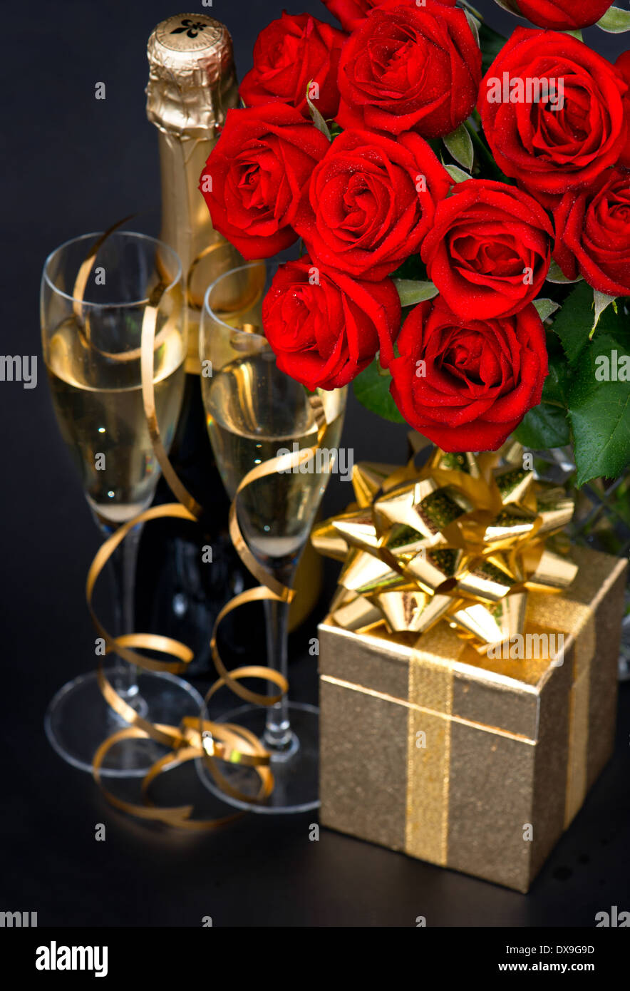 rote Rosen, goldenen Geschenk und und Champagner auf schwarzem Hintergrund. St. Valentines Day Karte Konzept Stockfoto