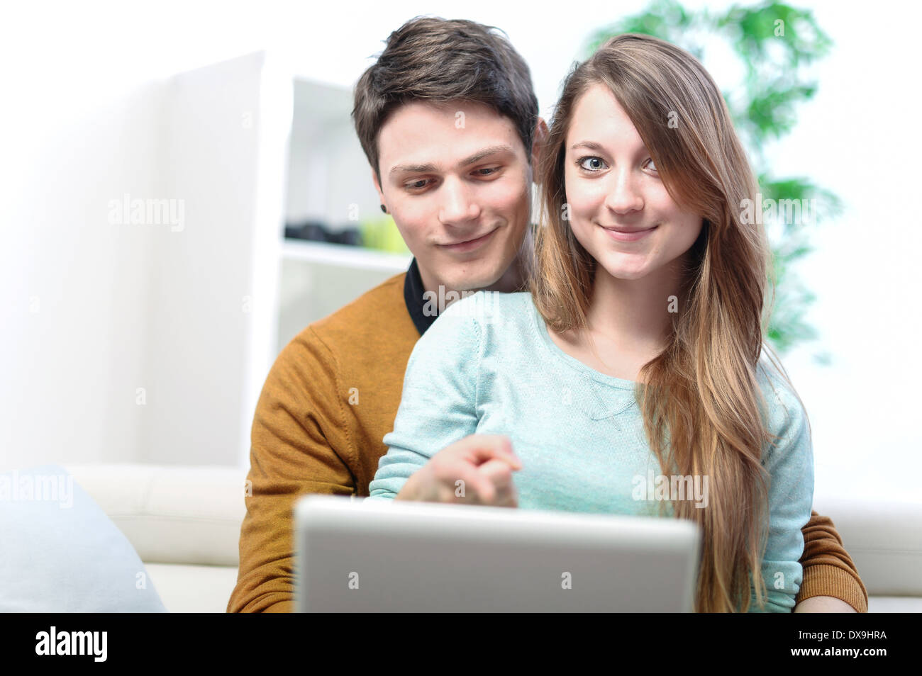 Porträt eines lächelnden jungen Paares mit Laptop zu Hause indoor Stockfoto