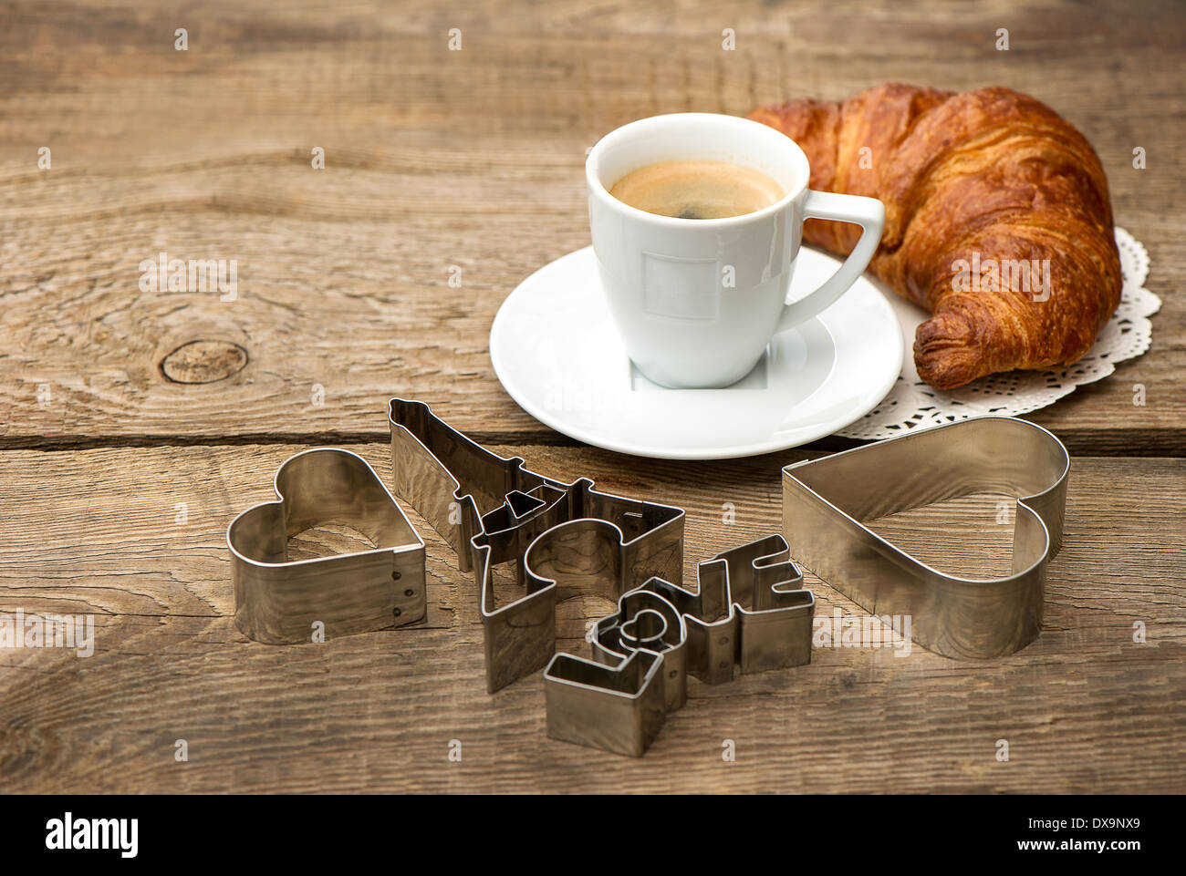Tasse schwarzer Kaffee mit Croissant und Herz Dekoration auf rustikalen hölzernen Hintergrund. romantisches französisches Frühstück. Zum Valentinstag Stockfoto