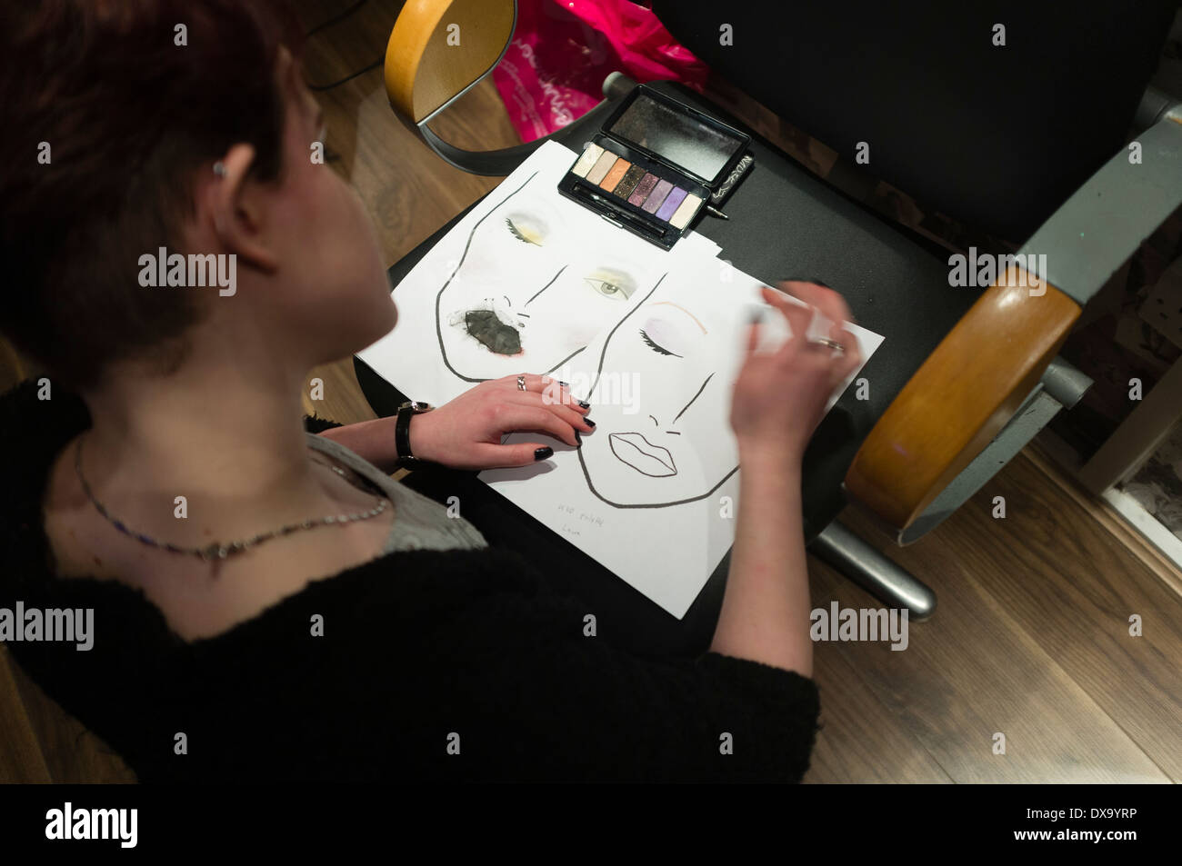 Eine junge Frau, die ihr Make-up mit einer Skizze eines Gesichts, UK Planung Stockfoto