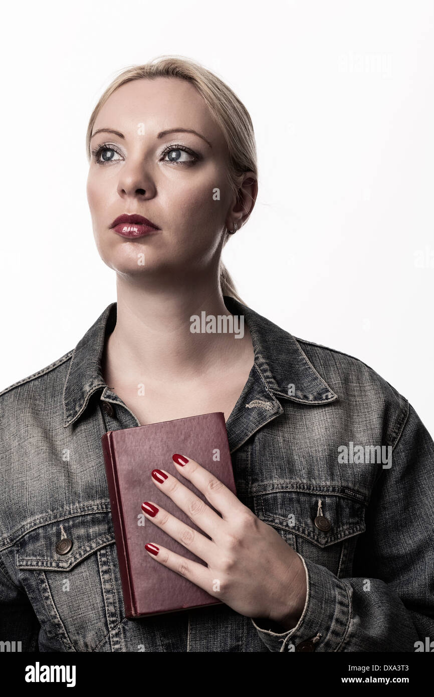 Blonde Frau mit alten Hardcover-Buch an ihre Brust nach oben in einer Pose andeutend Treue schwören Stockfoto