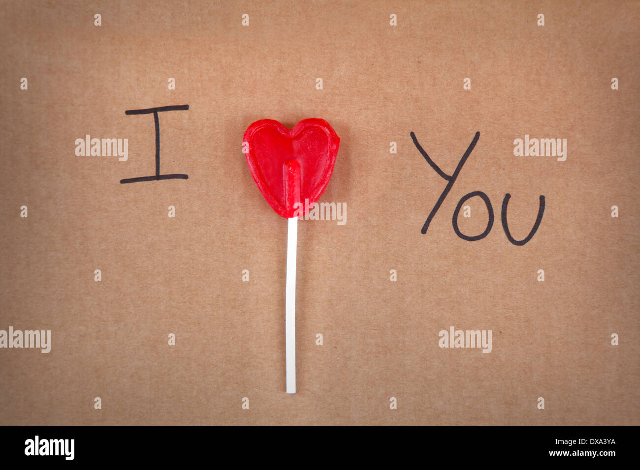 Ich liebe Sie Nachricht geschrieben einen Herz-Form-Lollipop auf Karton Stockfoto