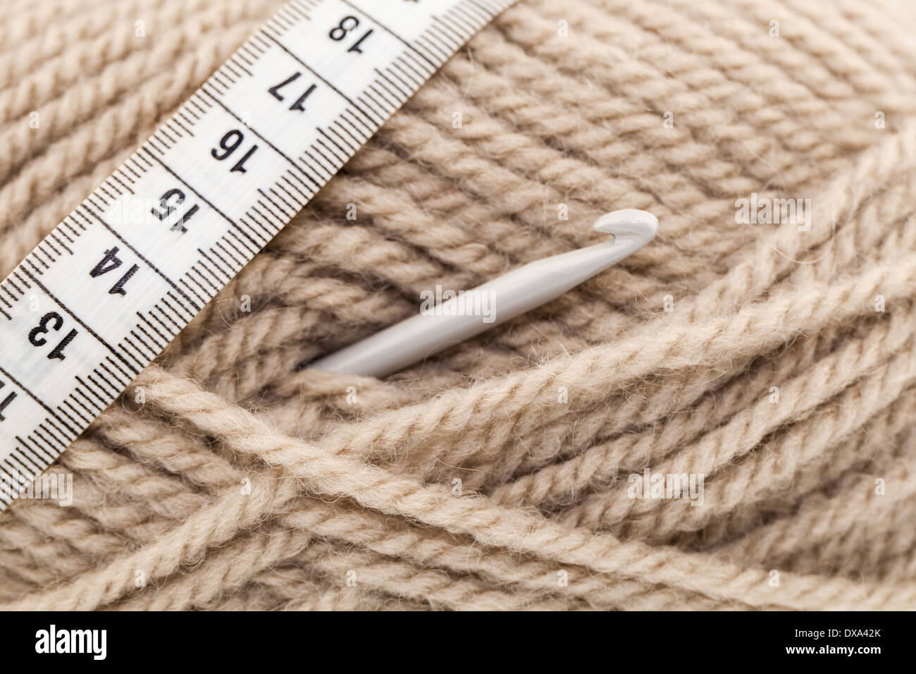 Nahaufnahme der Häkelnadel in einem Knäuel Beige. Stockfoto