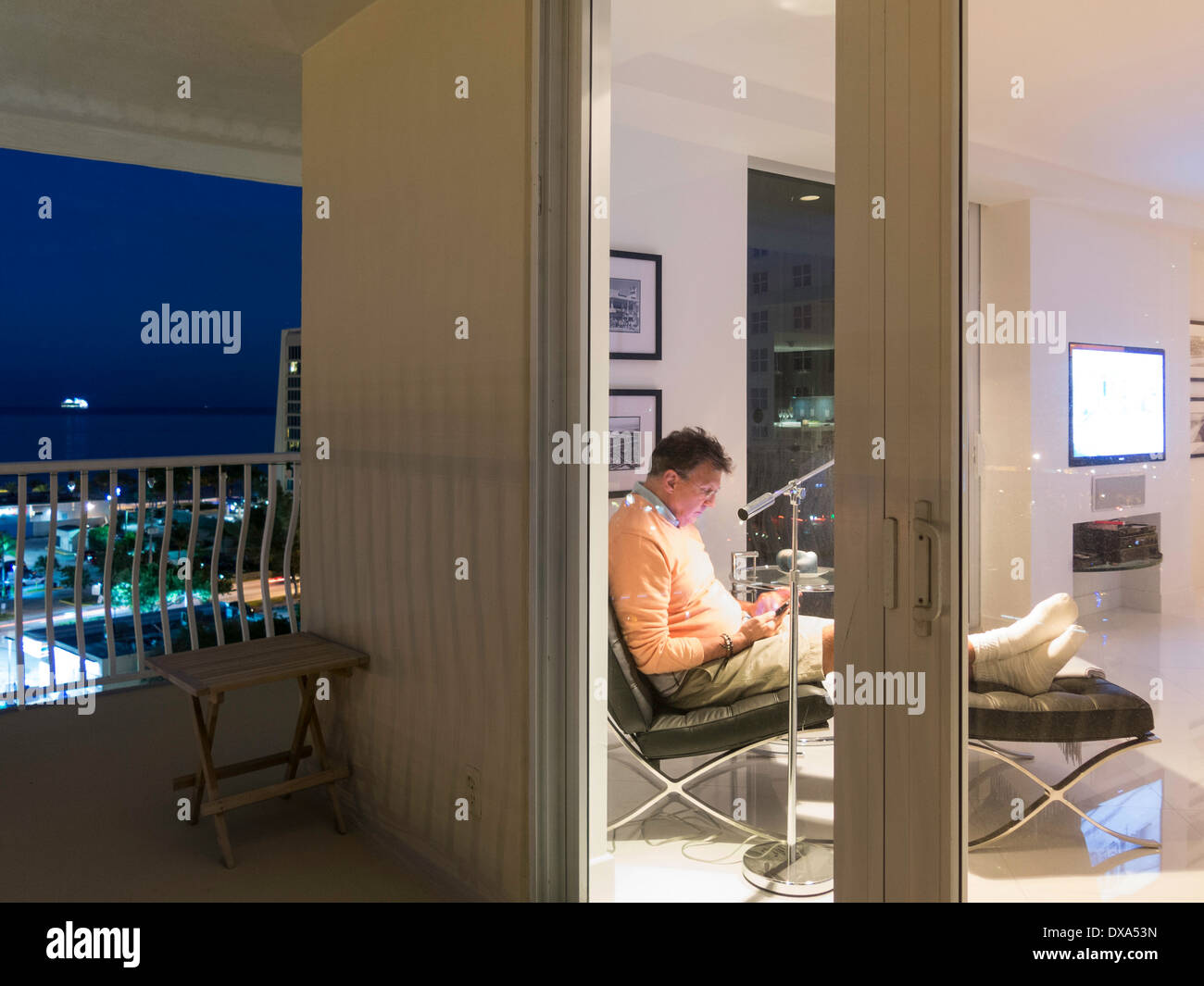 Reifer Mann Lesung in Luxus-Showcase-Eigentumswohnung, Blick vom Balkon in der Abenddämmerung, Fort Lauderdale, FL, USA Stockfoto