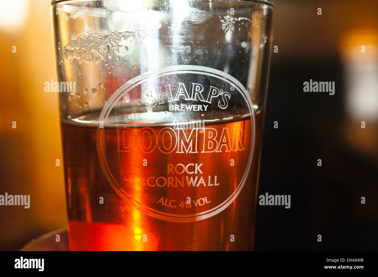 Eine teilweise leer gedruckten Glas Kleie Doom Bar real ale-Hintergrundbeleuchtung in einem graviertem Glas, pub Tabelle getränke Gläser Stockfoto