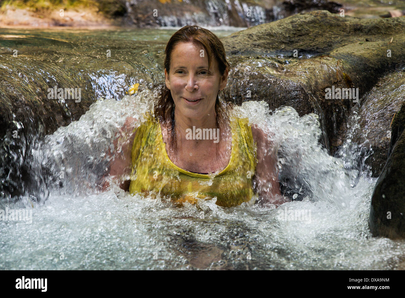 Frau genießt eine erfrischende Wassermassage im Mayfield Falls, Glenbrook, Jamaika Stockfoto