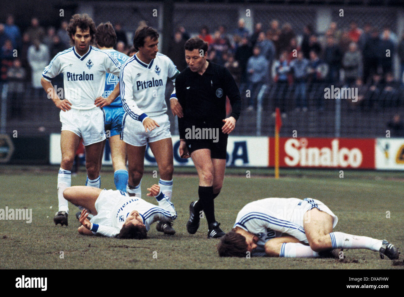 Fußball, Bundesliga, 1984/1985, Grotenburg Stadion, FC Bayer 05 Uerdingen vs. SV Waldhof Mannheim 2:2, Szene des Spiels, zwei Mannheimer Spieler verletzt auf Grund, hinter v.l.n.r.: Dieter Schlindwein (SVW), Teamleiter Günter Sebert (SVW), Schiedsrichter Anton Stockfoto