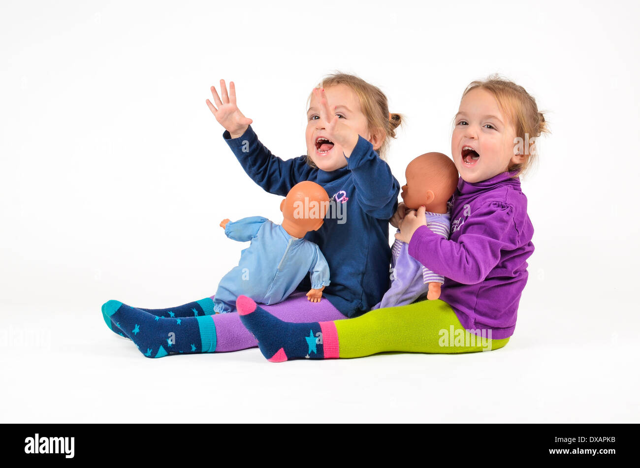 Zwillingen mit Puppen spielen und lachen Stockfoto