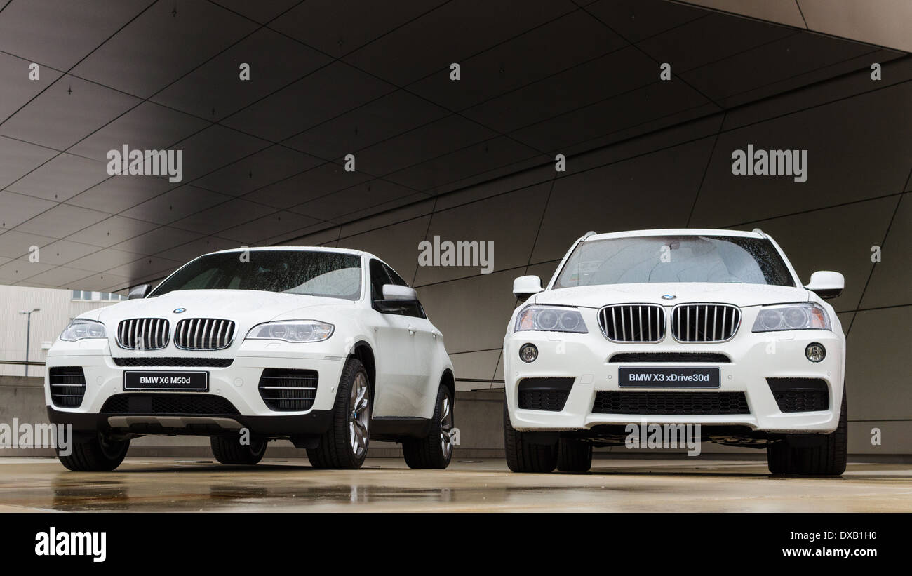 Zwei neue weiße BMW X 3 und X6 SUV in BMW Welt-Show präsentiert. Autos auf Podium nach Regen nass. Stockfoto