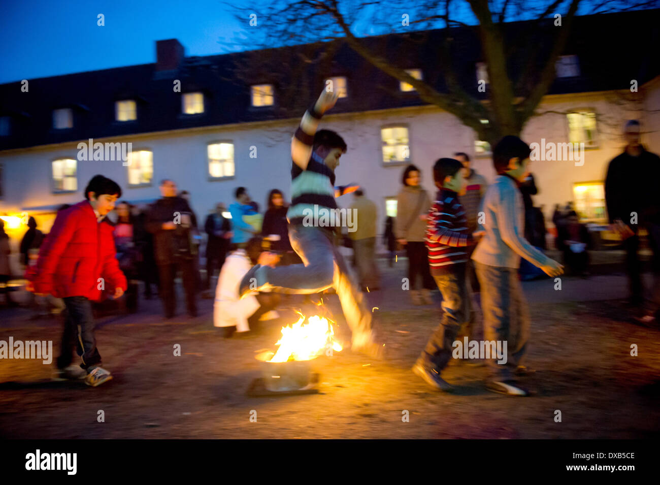 Berlin, Deutschland. 18. März 2014. Kinder springen über das Mittwoch-Licht (Chaharshanbe Suri) während der persischen Neujahrs Festivals "Nouruz" feierte der iranischen Gemeinschaft in Berlin, Deutschland, 18. März 2014. Es ist ein Vorspiel zu Nowruz, das jedes Jahr im Frühjahr stattfindet. Foto: Daniel Naupold/Dpa/Alamy Live News Stockfoto