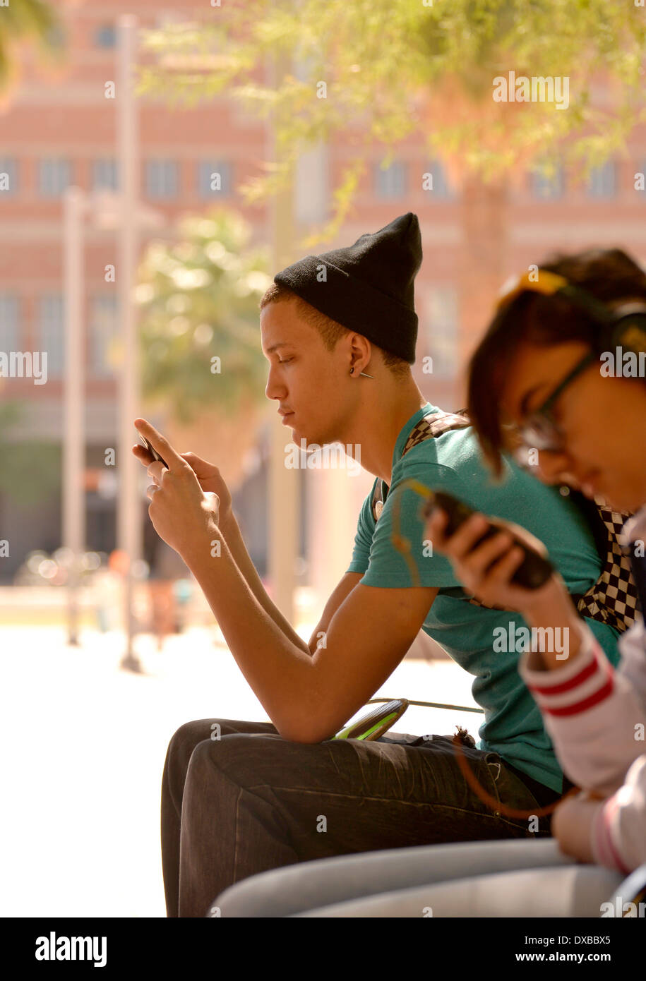 Ein junger Mann auf eine SMS auf einem Uni-Campus. Stockfoto