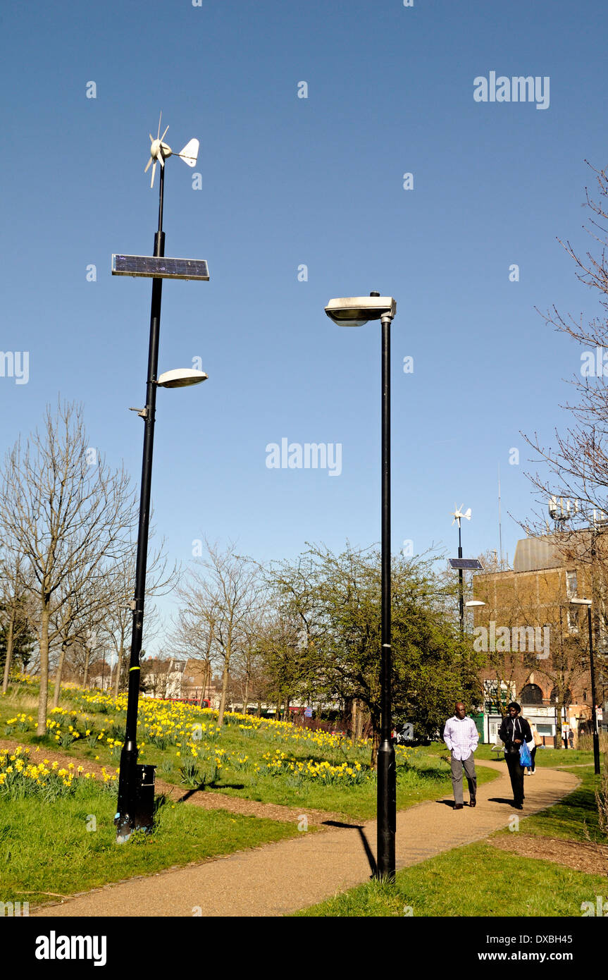 Wind und solar betriebene Laterne Lampe post neben konventionellen Laternenpfahl mit Passanten Mile End Park Tower Hamlets London Stockfoto