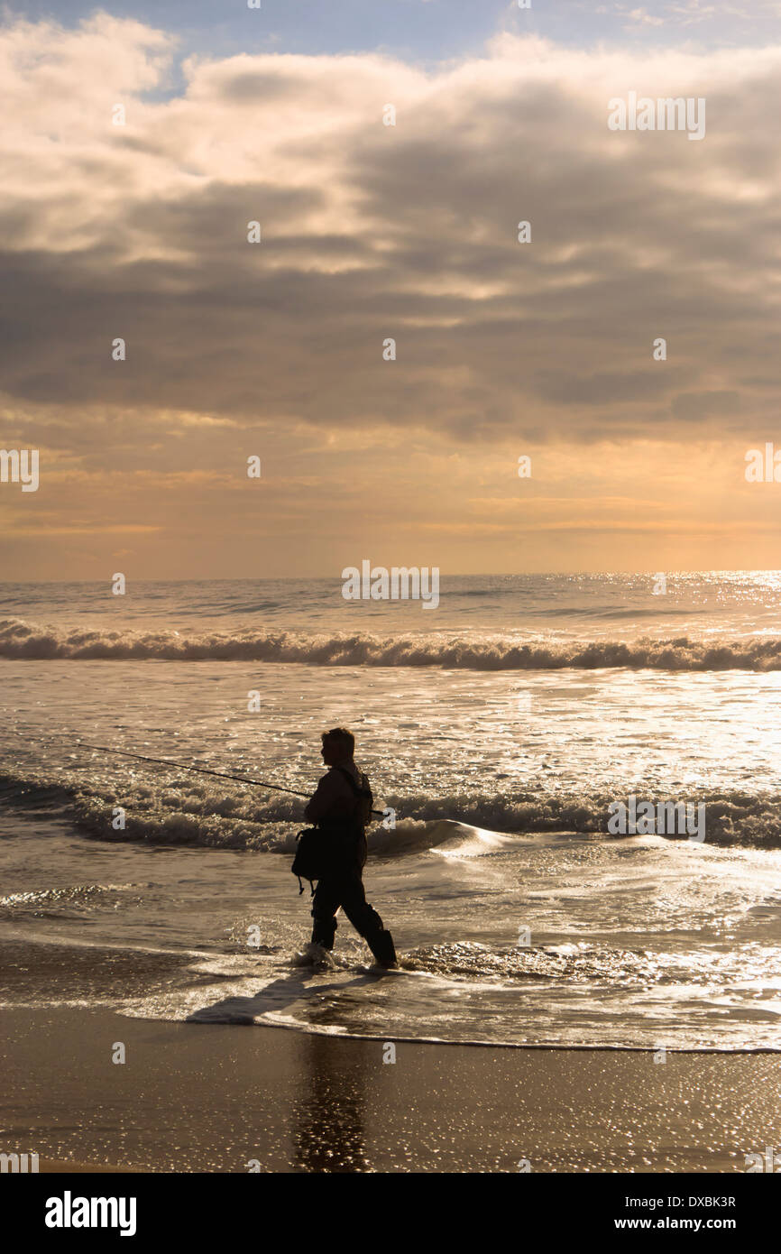 Provinz Cadiz, Costa De La Luz, Andalusien, Spanien. Silhouette der Mann Angeln im Meer bei Sonnenuntergang. Stockfoto